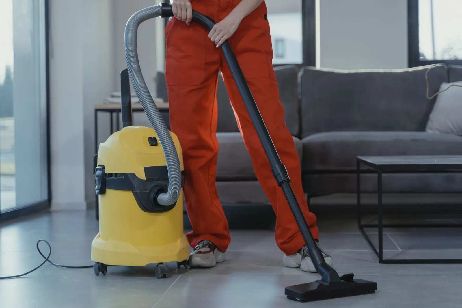 Professional cleaner vacuuming a modern living room